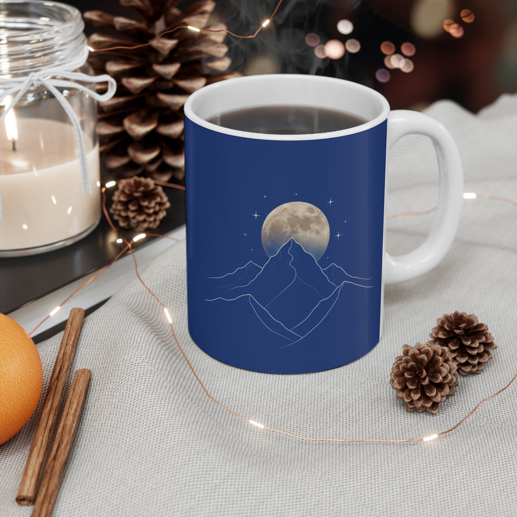 Minimalist line art coffee mug featuring blue design with mountains and moon, surrounded by cozy decorations.